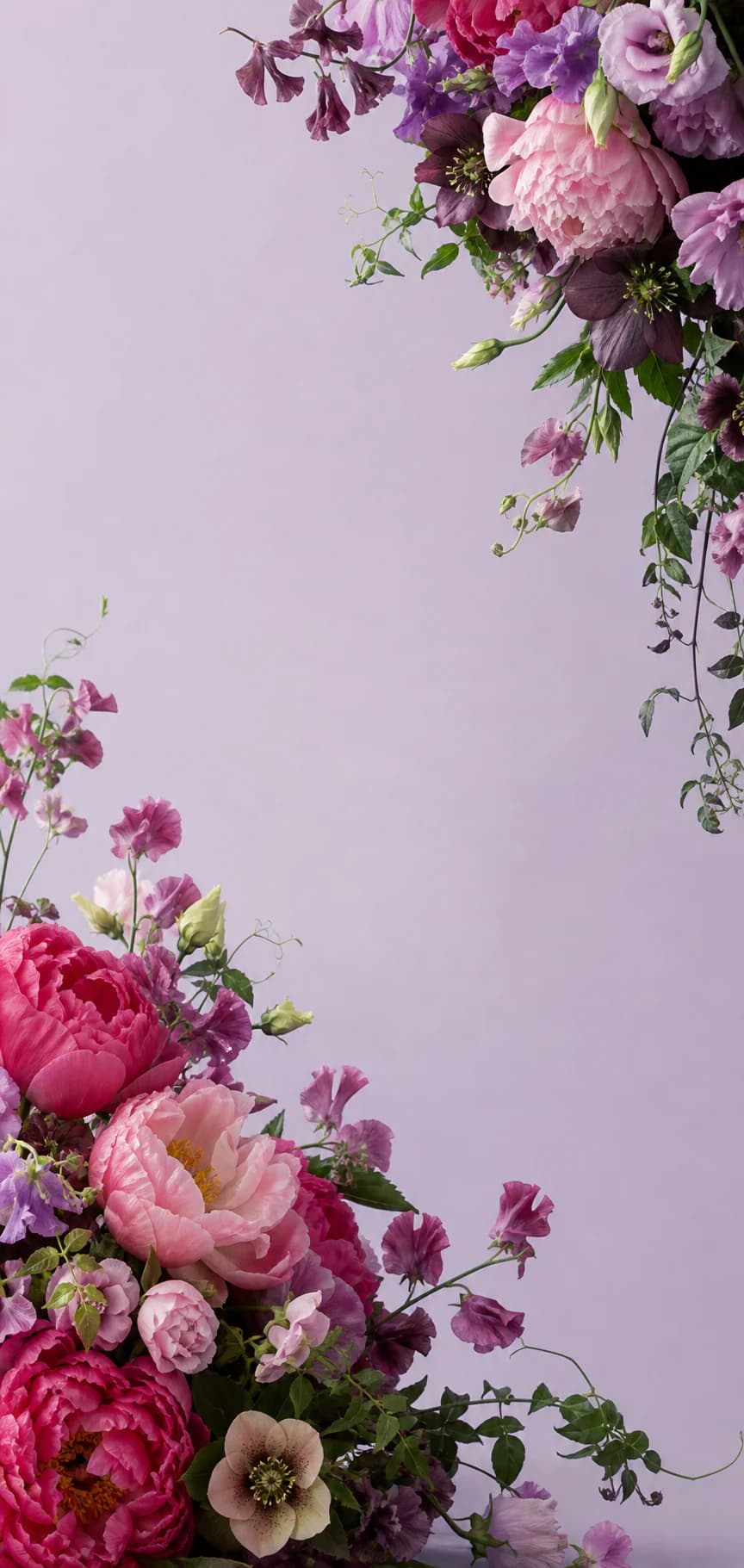 An abundant arrangement of raspberry, lilac, plum, and pink flowers with trailing greenery